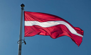 The Flag of Latvia waving in the wind with a clear blue sky.