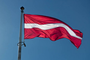 The Flag of Latvia waving in the wind with a clear blue sky.